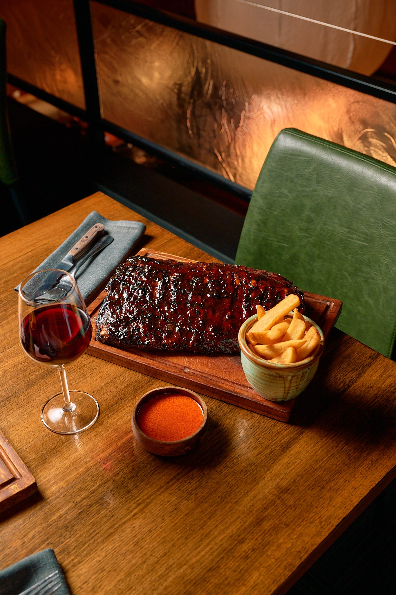 Glazed ribs with chips and red wine on a wooden table
